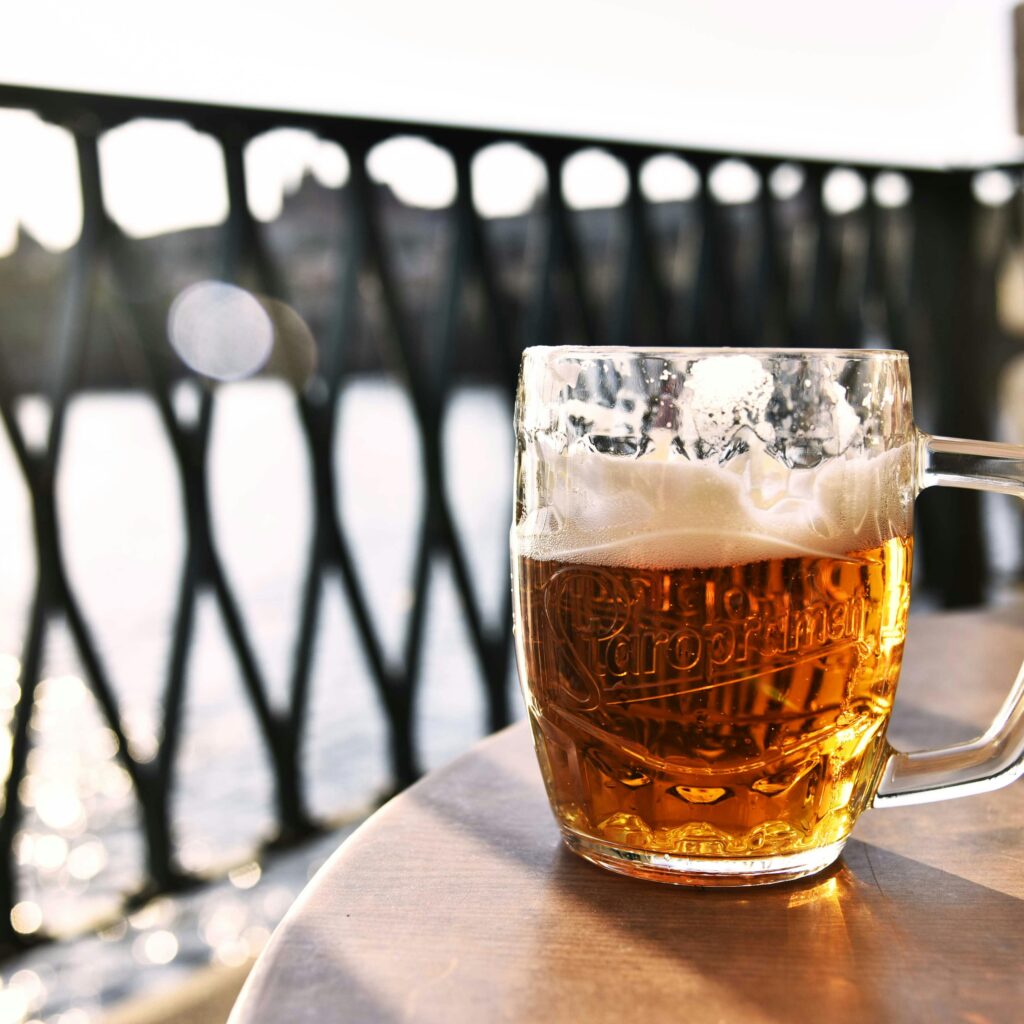 Refreshing lager beer mug outdoors in Prague with scenic river view.